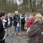 Eine Gruppe Menschen ist im Wald und schaut sich die Wildschweinroute an
